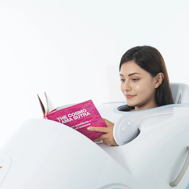 A woman relaxing inside the U-MINE BodyJet steam spa while reading a book.